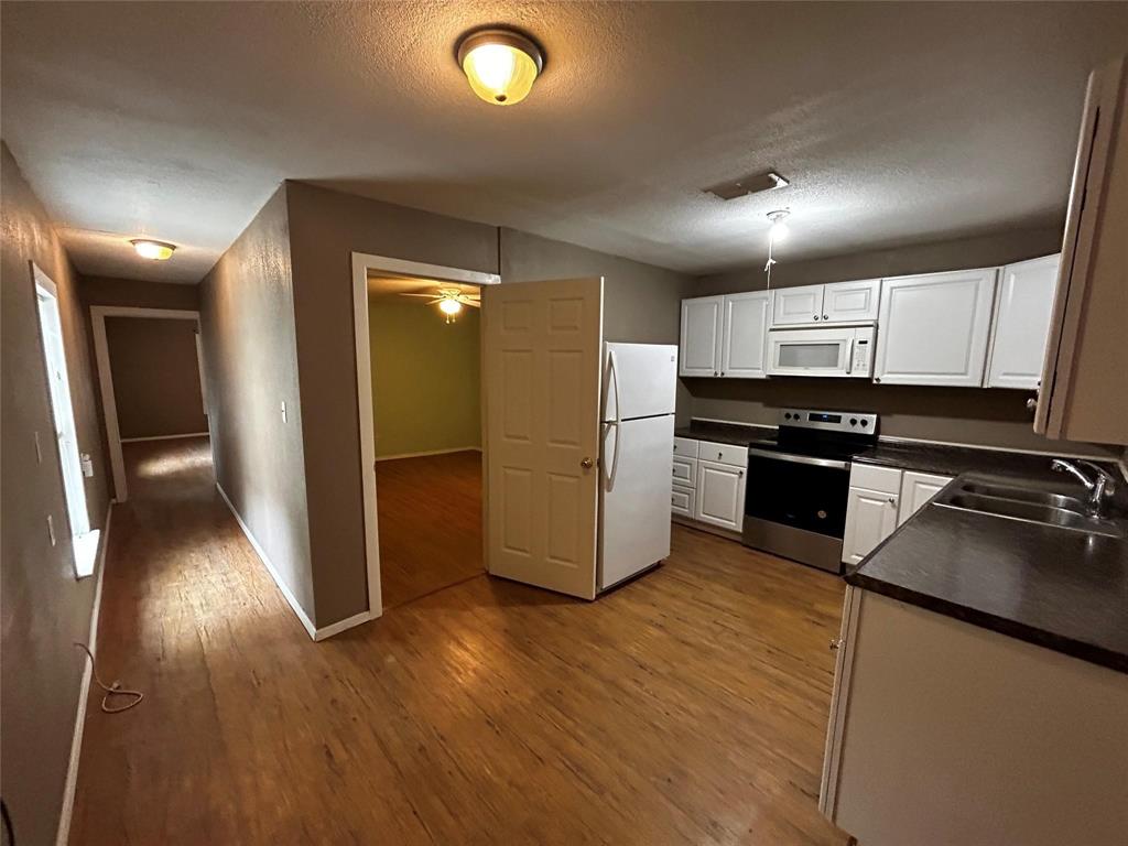 910 West Long, Unit A Stephenville, TX 76401 - Photo 7 of 39 a kitchen with stainless steel appliances granite countertop a refrigerator a sink and wooden floor