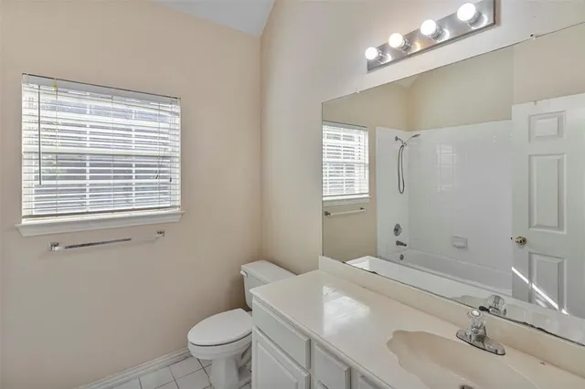 a bathroom with a sink a toilet a mirror a vanity and window