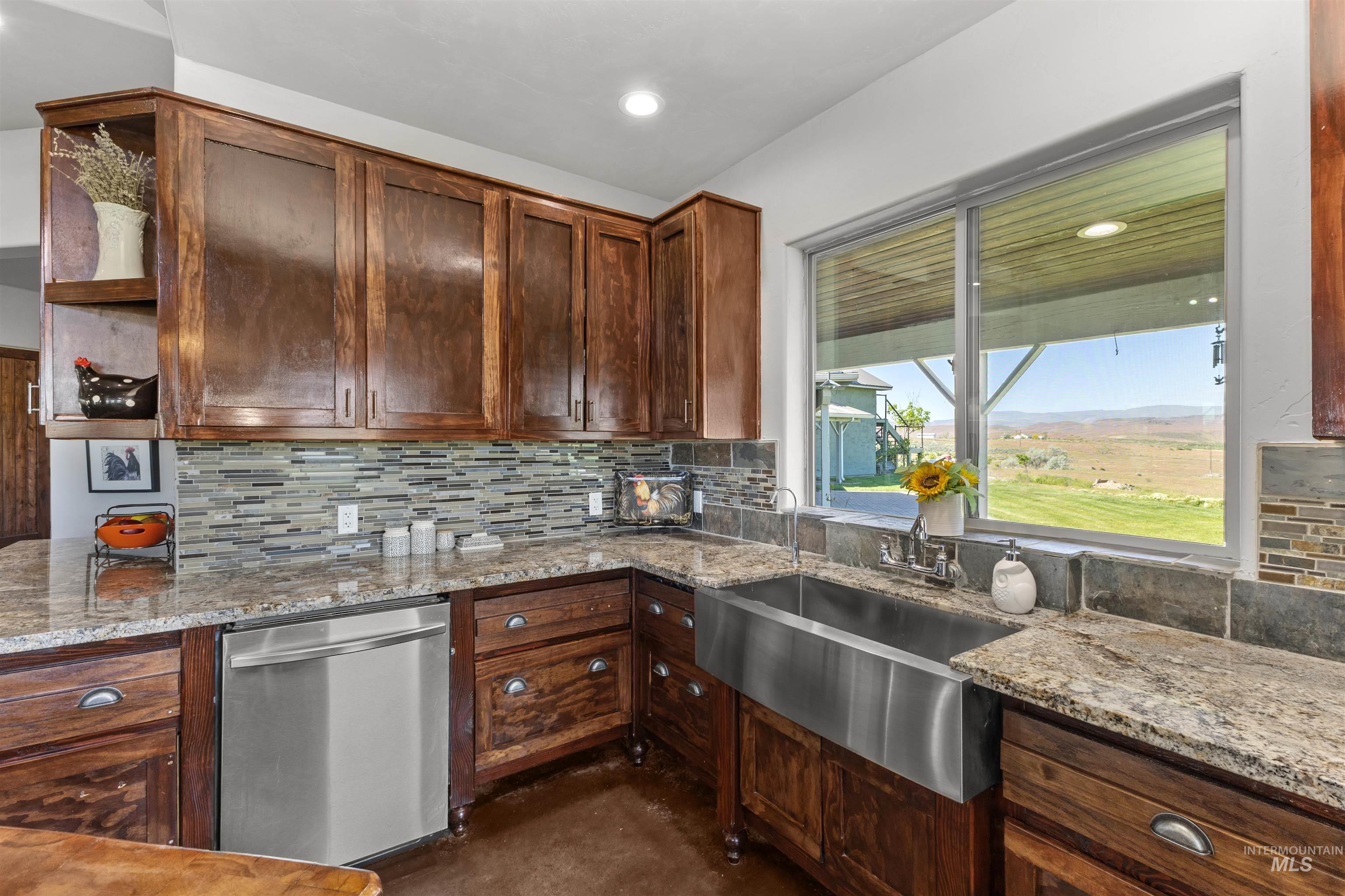 1030 Desert Glen Road Adrian, OR 97901 - Photo 29 of 47 Kitchen featuring wood cabinetry, a stainless steel farmhouse sink, granite countertops, a mosaic tile backsplash, and an integrated stainless steel dishwasher
