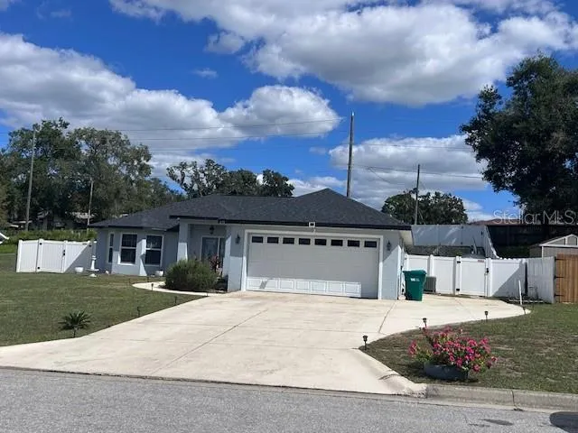a view of a white house with a big yard and large tree