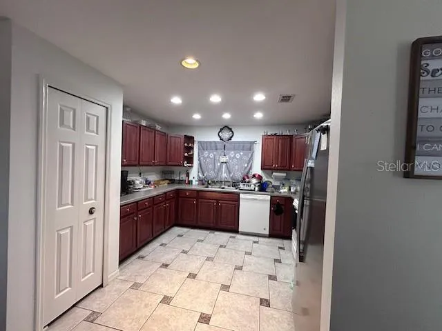 a large kitchen with stainless steel appliances kitchen island granite countertop a refrigerator and a sink