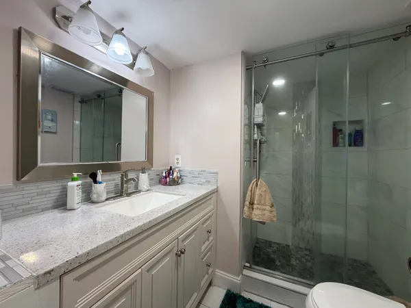 a bathroom with a sink shower and a mirror