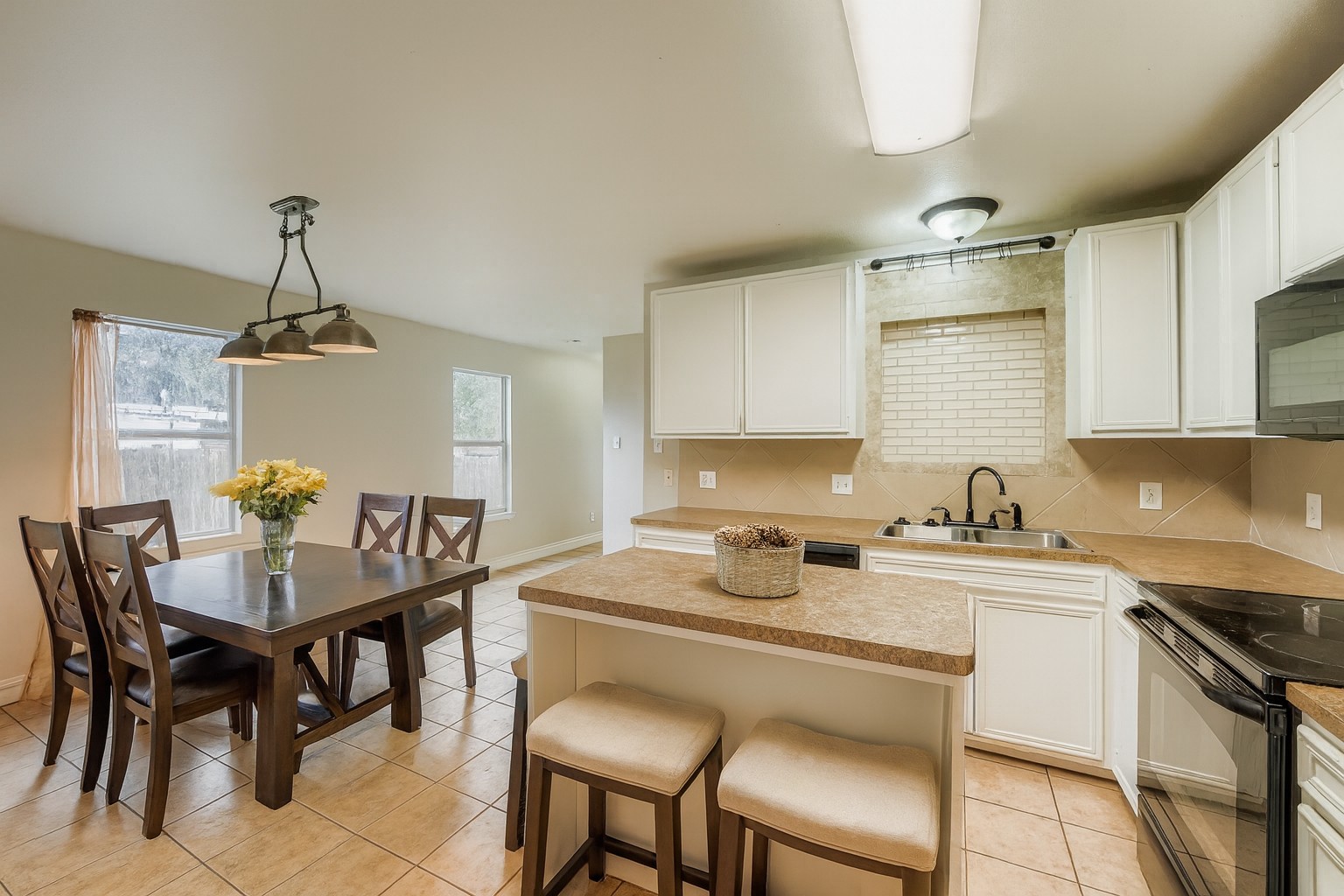 304 South Main Street Elgin, TX 78621 - Photo 2 of 25 Virtually staged -Kitchen featuring black appliances, white cabinets, decorative light fixtures, a center island, and backsplash