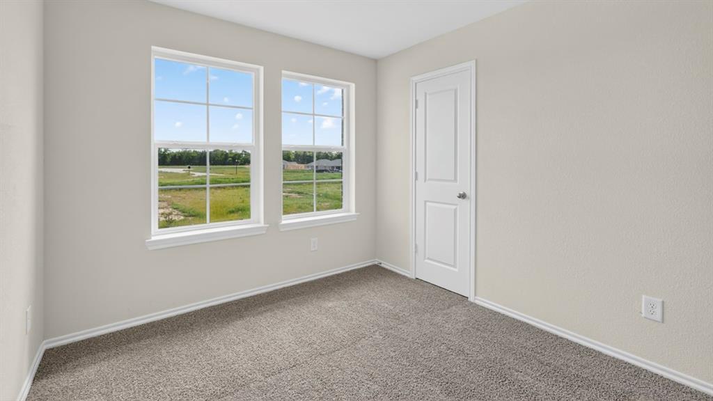 4008 Ripplewood Drive Lindale, TX 75771 - Photo 10 of 37 Room featuring two large windows with white trim, light gray textured walls, gray carpet, and a white interior door