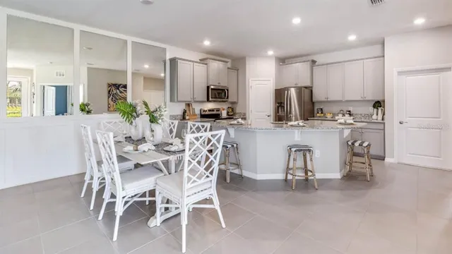 a kitchen with stainless steel appliances kitchen island granite countertop a dining table chairs sink and cabinets