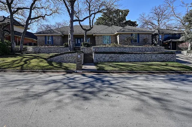 a view of a house with a yard and large tree