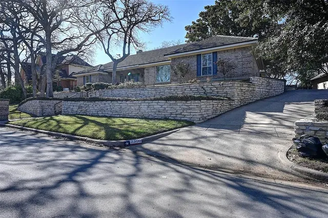 a view of a house with a small yard plants and large tree