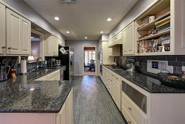 a large kitchen with stainless steel appliances granite countertop a large counter top a stove and a sink