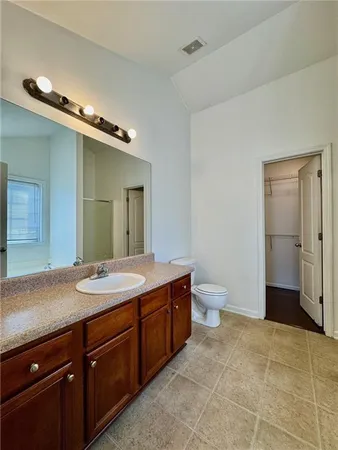 a spacious bathroom with a granite countertop sink a toilet and a mirror