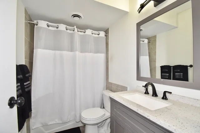a bathroom with a granite countertop sink toilet and shower