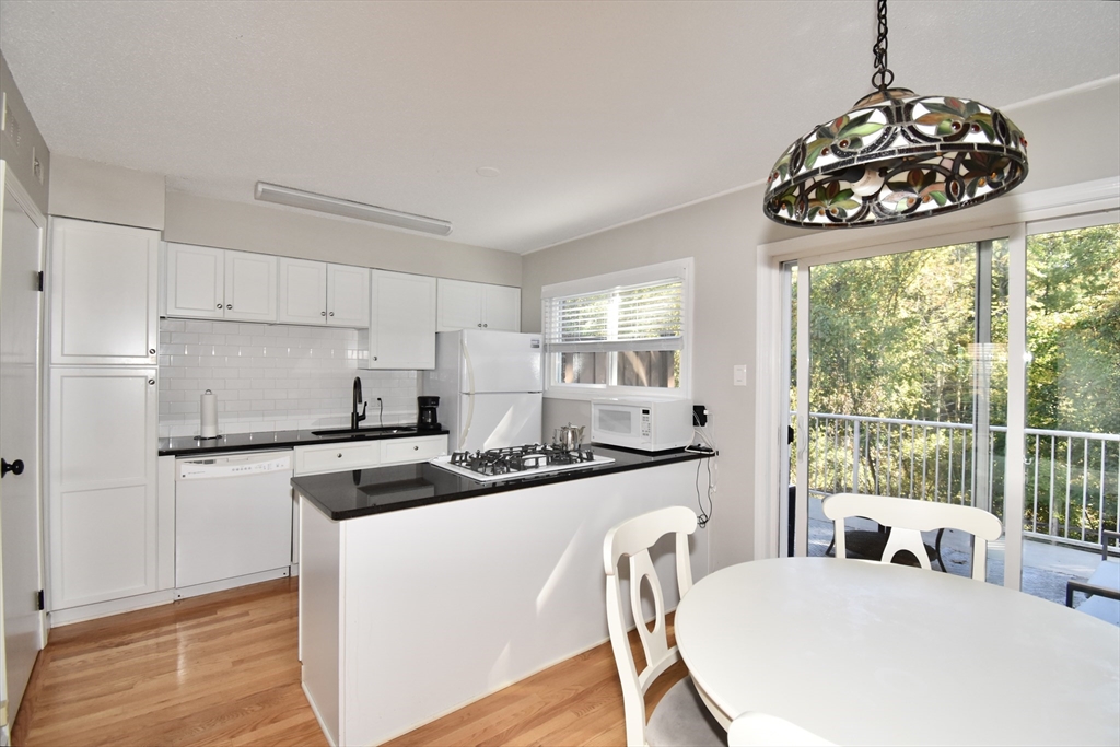 15 Yorktown Drive, Unit 15 Springfield, MA 01108 - Photo 8 of 22 a kitchen with stainless steel appliances granite countertop a stove a sink a refrigerator and a dining table with wooden floor