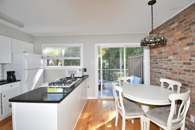 a kitchen with stainless steel appliances granite countertop a stove a refrigerator a kitchen island a dining table and chairs