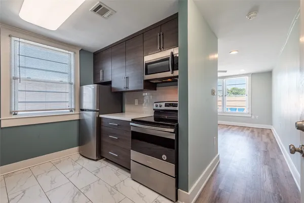 a kitchen with stainless steel appliances cabinets and a wooden floor