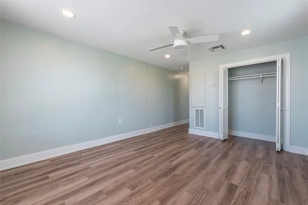an empty room with wooden floor a ceiling fan and staircase