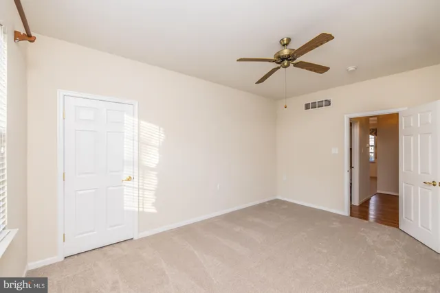 a view of an empty room and chandelier fan
