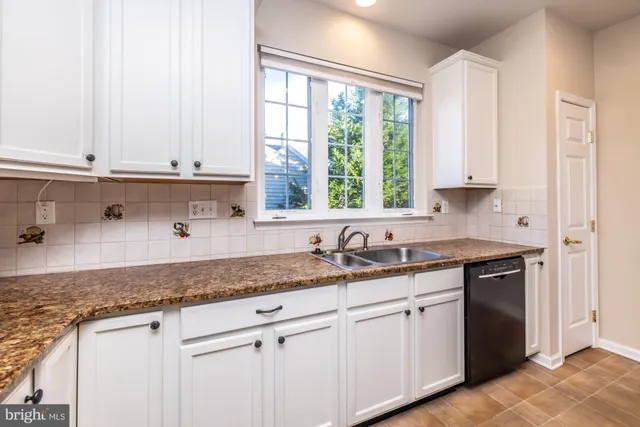a kitchen with granite countertop white cabinets and a window