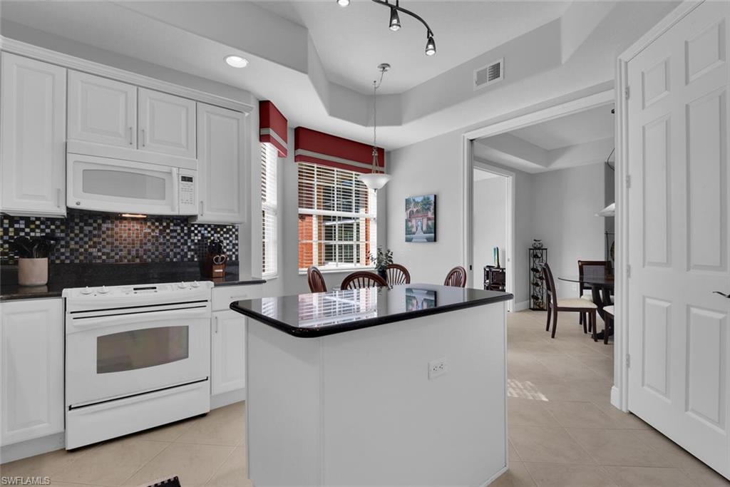 6413 Legacy Circle, Unit 1602 Naples, FL 34113 - Photo 12 of 34 a kitchen with a stove and white cabinets