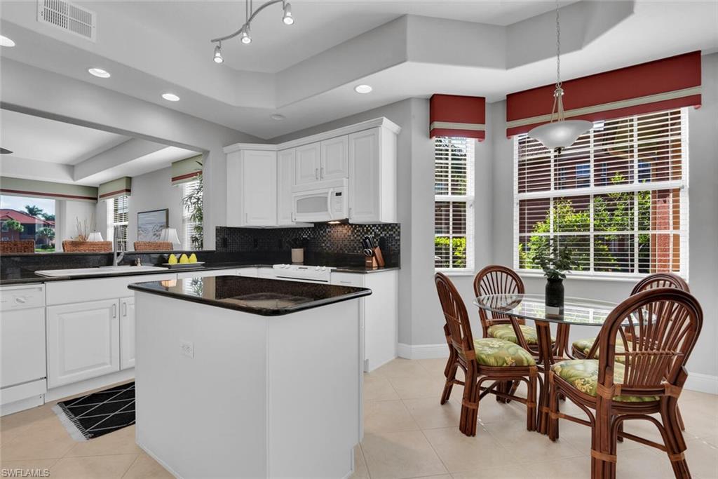 6413 Legacy Circle, Unit 1602 Naples, FL 34113 - Photo 15 of 34 a kitchen with a dining table chairs and white appliances