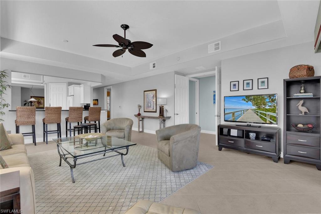6413 Legacy Circle, Unit 1602 Naples, FL 34113 - Photo 10 of 34 a living room with furniture and a flat screen tv with the kitchen view