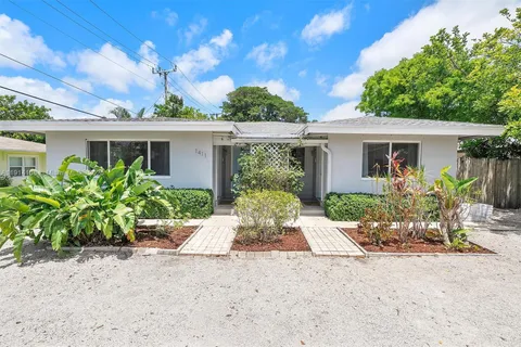 front view of house with potted plants and a large tree