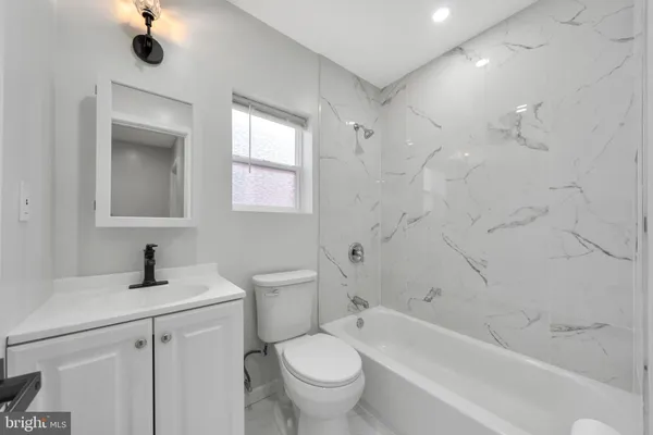 a bathroom with a sink mirror toilet and window