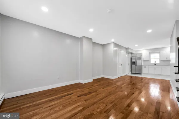 a view of an empty room with wooden floor and window