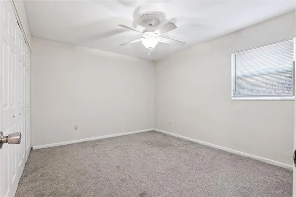 an empty room with a chandelier fan and windows