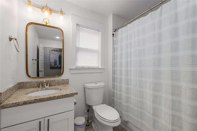 a bathroom with a granite countertop sink a toilet and a mirror