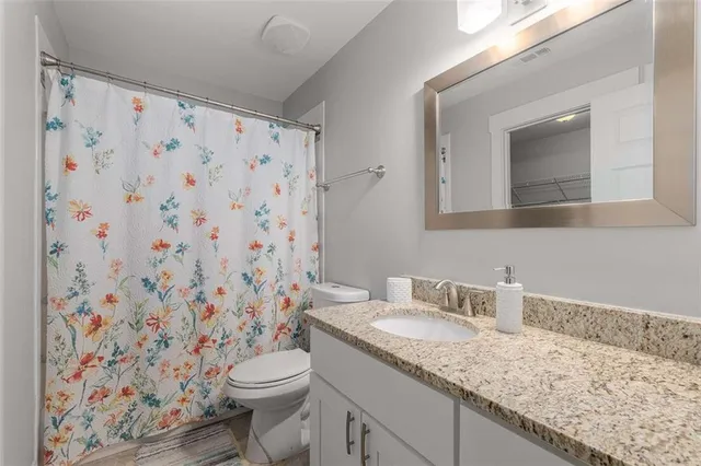 a bathroom with a granite countertop sink a toilet and a mirror