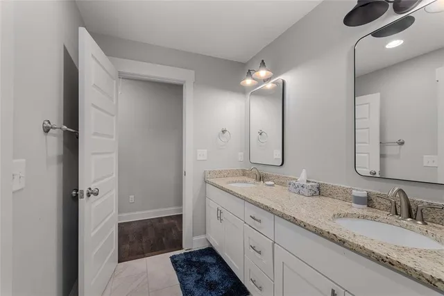 a bathroom with a granite countertop double vanity sink and mirror