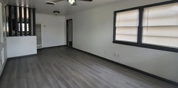 a view of an empty room with wooden floor and a window