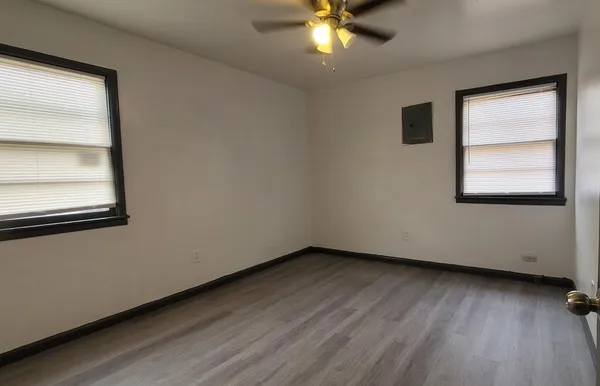 an empty room with wooden floor and windows