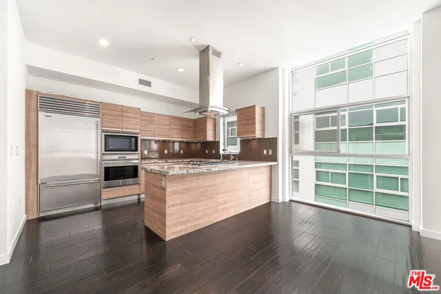 a view of kitchen with stainless steel appliances wooden floor and large window
