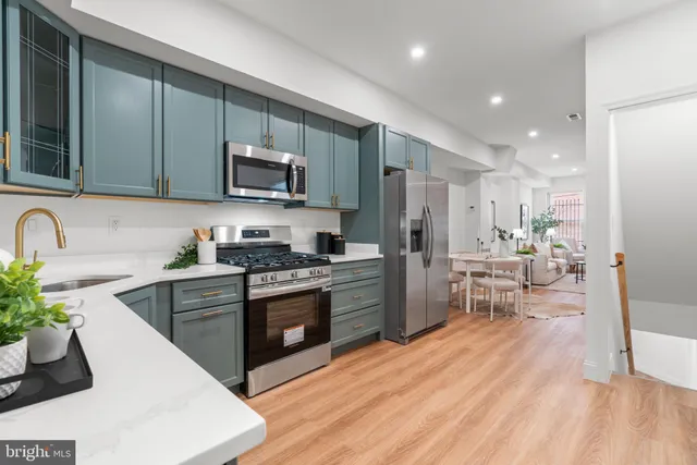 a kitchen with stainless steel appliances granite countertop wooden cabinets a sink dishwasher a stove and a refrigerator with wooden floor