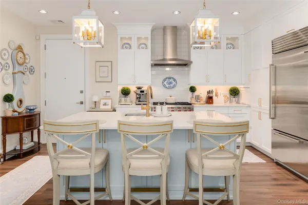 a kitchen with stainless steel appliances kitchen island granite countertop a dining table chairs and a refrigerator