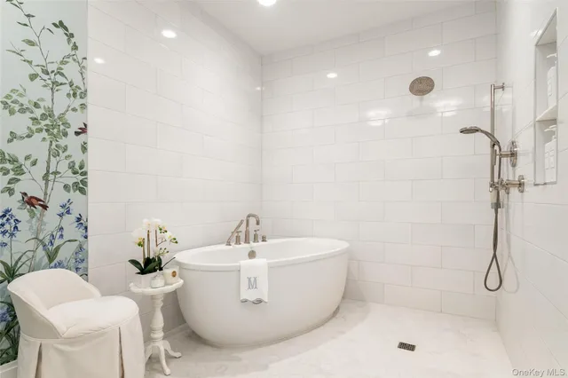 a white bath tub sitting next to a white sink and a shower