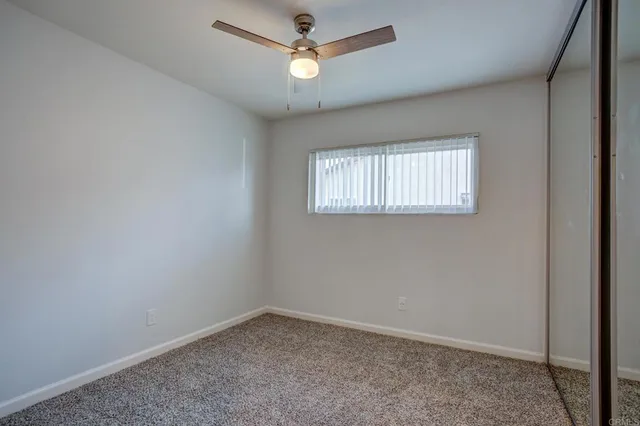 an empty room with a window and a fan