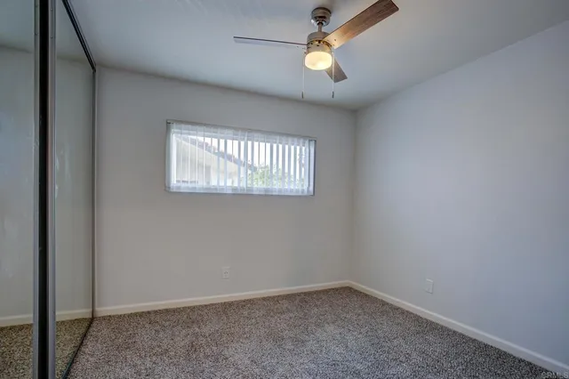 an empty room with a window and a ceiling fan