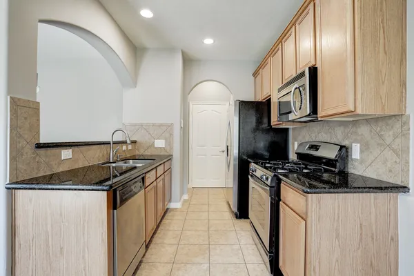 a kitchen with stainless steel appliances granite countertop a stove a sink and a refrigerator