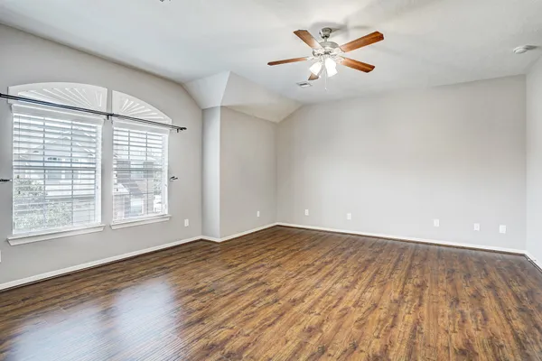 an empty room with wooden floor and windows