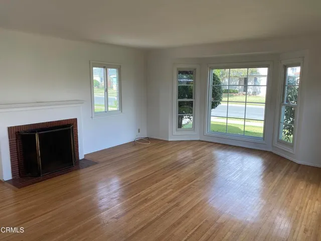 an empty room with wooden floor and fireplace