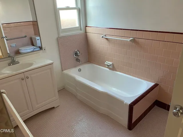 a bathroom with a tub a sink and a mirror