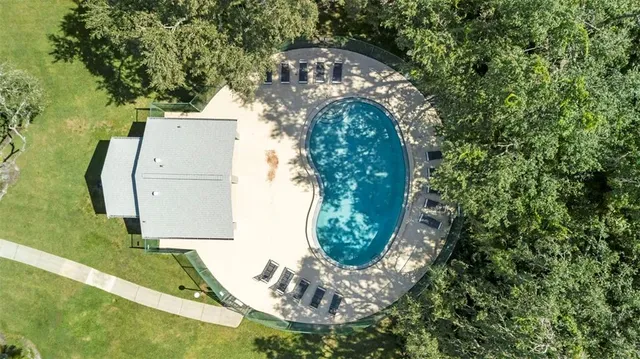 an aerial view of a residential houses with outdoor space and trees
