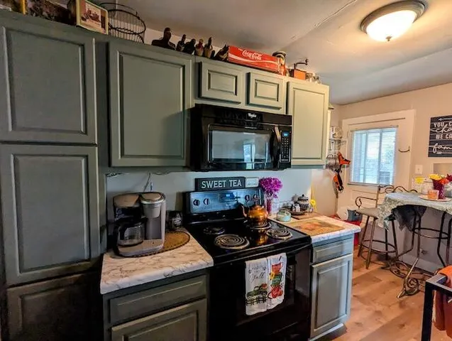 a kitchen with stainless steel appliances granite countertop a stove top oven a refrigerator a dining table and chairs with wooden floor