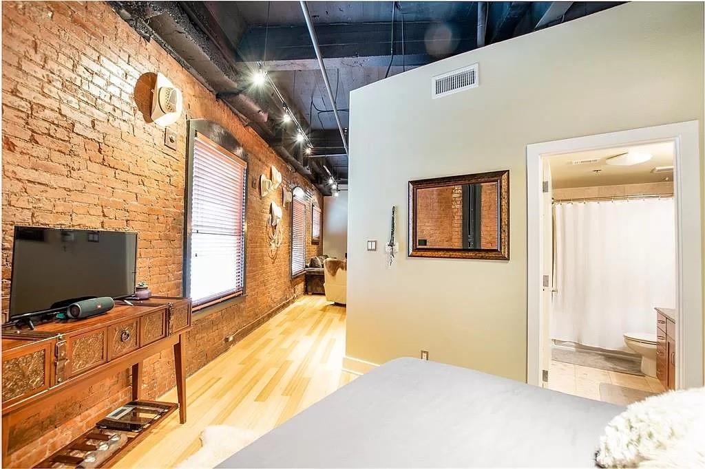 910 Houston Street, Unit 604 Fort Worth, TX 76102 - Photo 14 of 14 Bedroom featuring brick wall and light wood-style flooring
