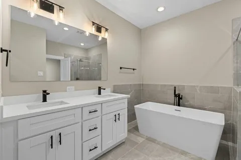 a bathroom with a double vanity sink a mirror and a bathtub