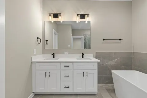 a bathroom with a double vanity sink a toilet and a bathtub