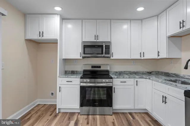 a kitchen with granite countertop white cabinets and stainless steel appliances