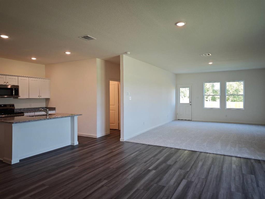2111 Burnwood Street Melissa, TX 75454 - Photo 3 of 18 a view of a kitchen and an empty room with wooden floor and windows