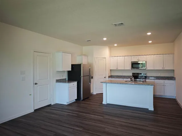 a kitchen with stainless steel appliances granite countertop a refrigerator and a stove top oven